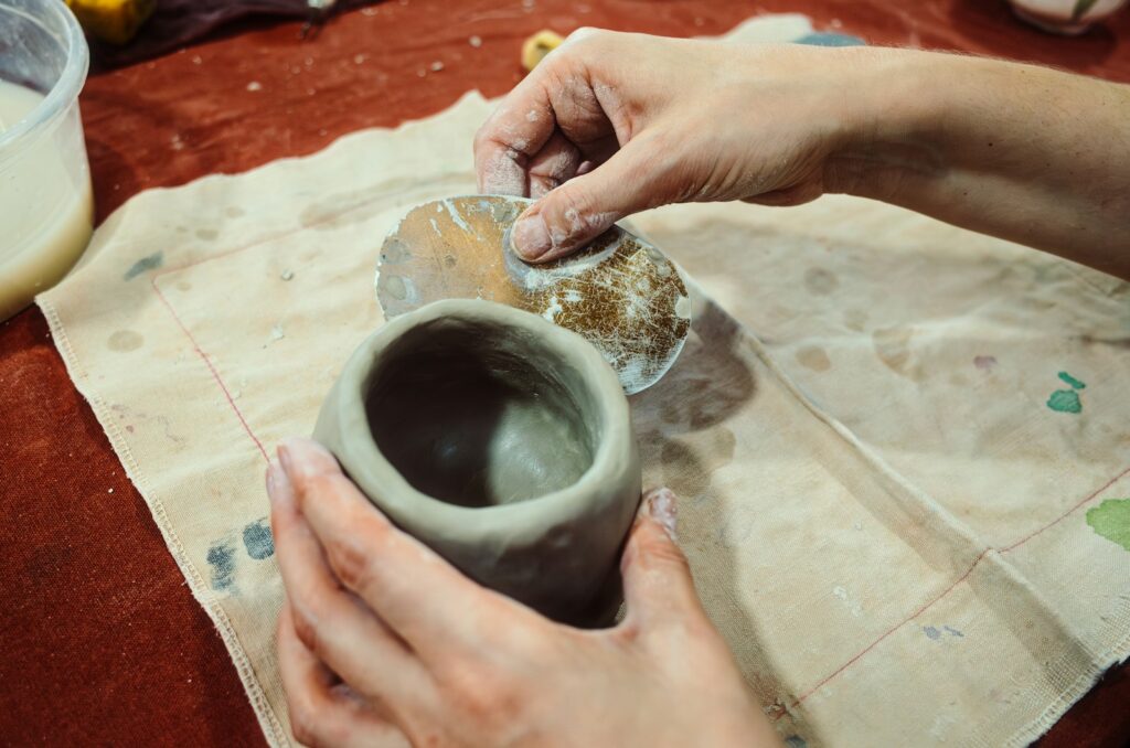 a person is making a vase out of clay